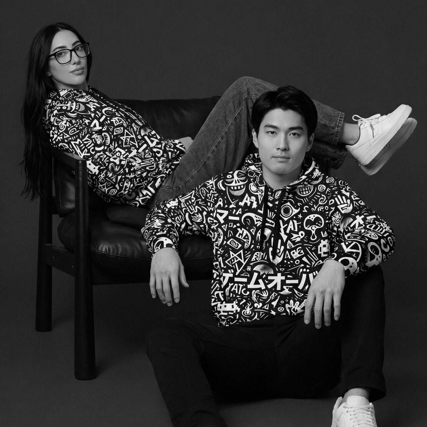 Two people wearing matching patterned outfits sitting on a dark background