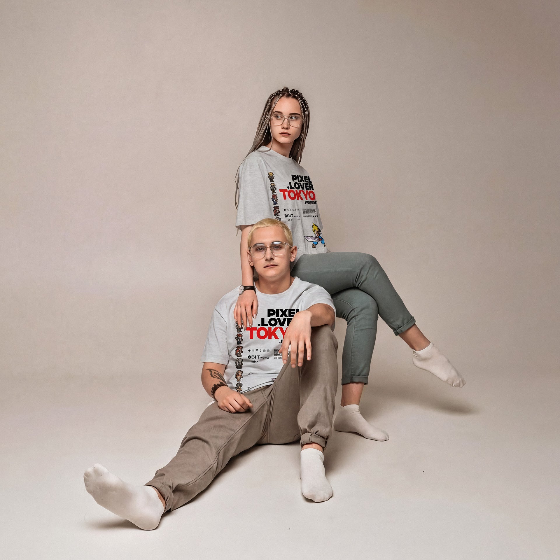 Two people wearing matching t-shirts sitting on a plain background