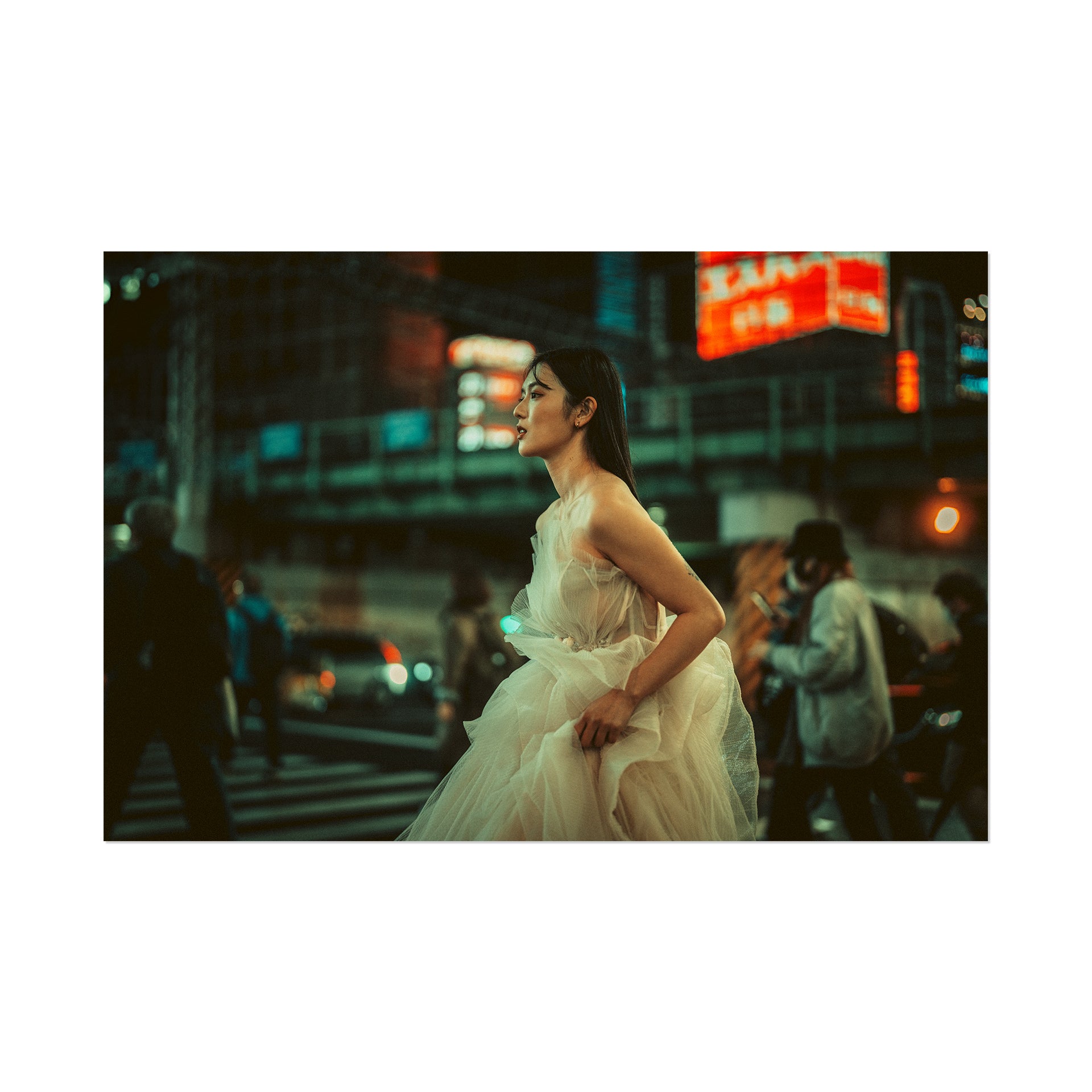 Woman in a white dress standing on a city street at night with neon signs in the background