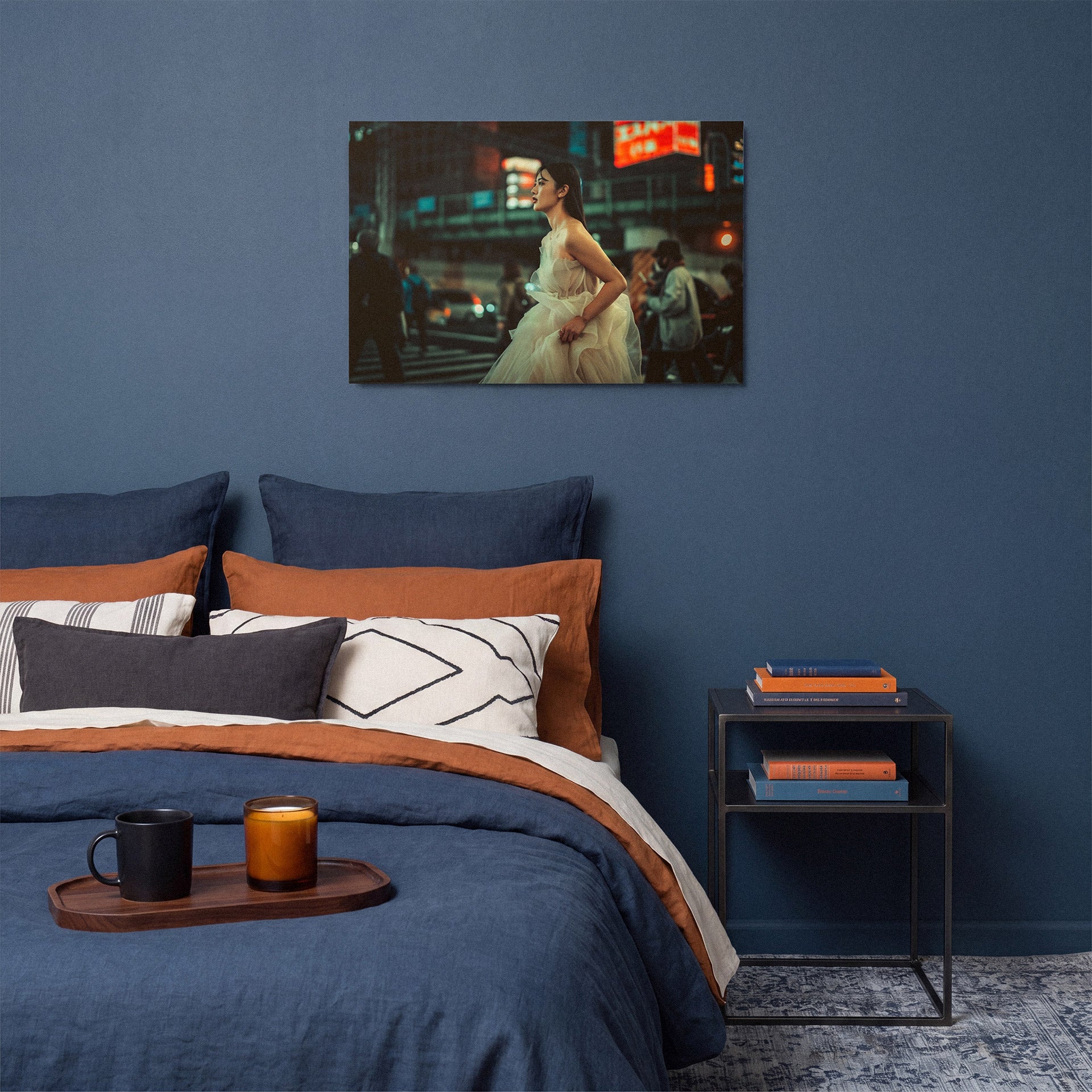 Bedroom with blue walls, a bed with orange and blue bedding, and a framed photograph on the wall.